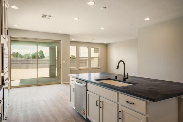 6209 Angelou Ln NW, Albuquerque, NM 87120 - kitchen with a sink, stainless steel dishwasher, light wood-style floors, recessed lighting, and white cabinetry