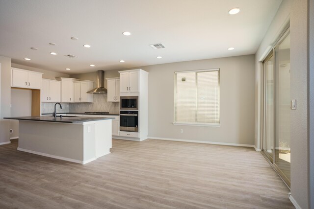 6209 Angelou Ln NW, Albuquerque, NM 87120 - kitchen featuring wall chimney range hood, stainless steel oven, built in microwave, decorative backsplash, and dark countertops