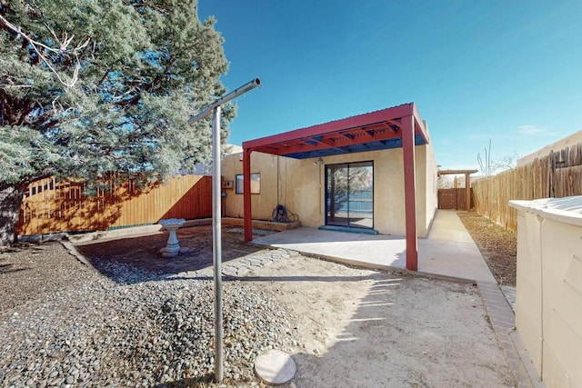 rear view of property with stucco siding, a fenced backyard, and a patio