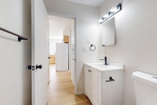 half bath featuring toilet, wood finished floors, and vanity