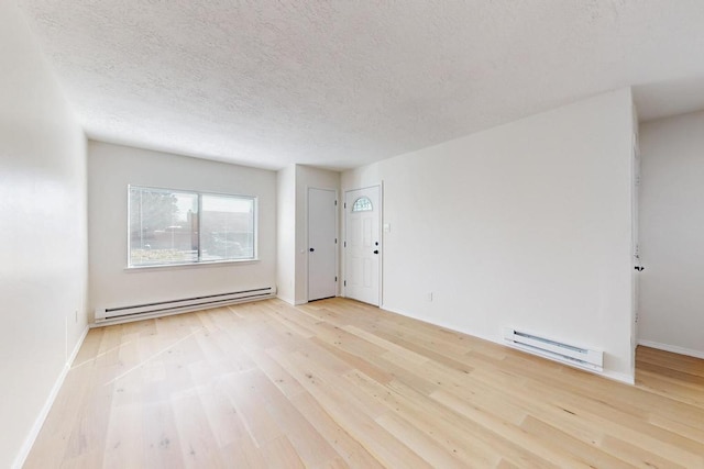 empty room with baseboards, a textured ceiling, a baseboard heating unit, and wood finished floors