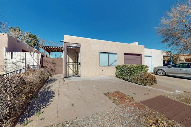 southwest-style home featuring a gate, fence, and stucco siding