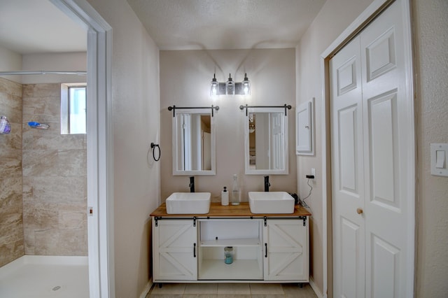 bathroom with double vanity, tiled shower, and a sink