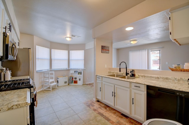 kitchen featuring baseboards, light tile patterned flooring, white cabinets, stainless steel appliances, and a sink