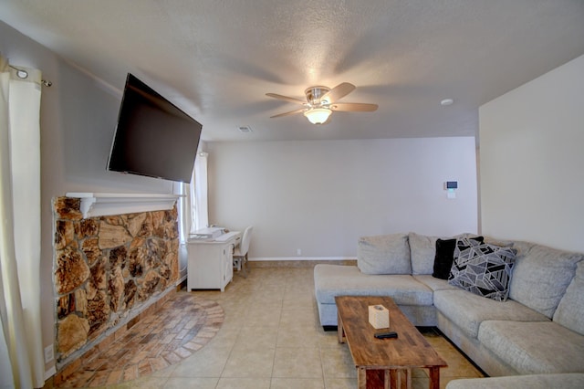 living room with visible vents, baseboards, ceiling fan, a fireplace, and light tile patterned flooring