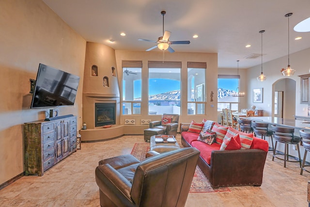 living area with arched walkways, a large fireplace, visible vents, and recessed lighting