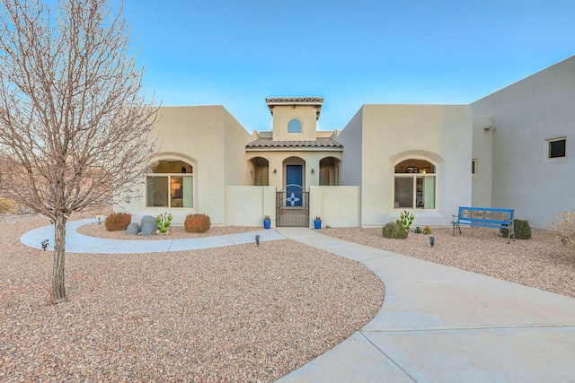 view of front facade featuring a gate, a tile roof, and stucco siding