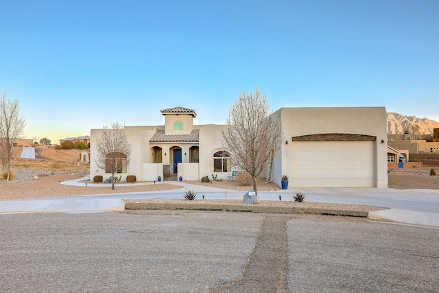 view of front of property with a garage, concrete driveway, a tile roof, and stucco siding