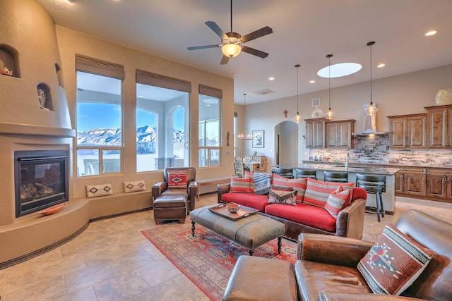 living area with arched walkways, recessed lighting, a ceiling fan, visible vents, and a glass covered fireplace