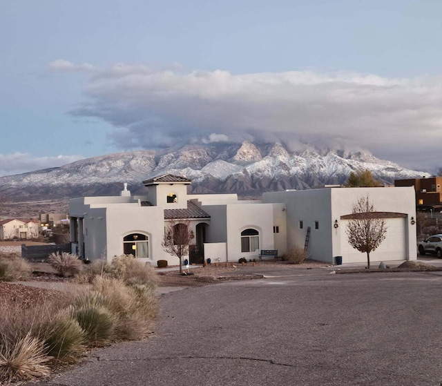 view of front of home with a garage, a mountain view, driveway, and stucco siding