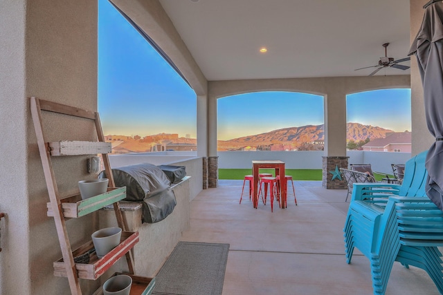 view of patio / terrace featuring a ceiling fan, a mountain view, and fence