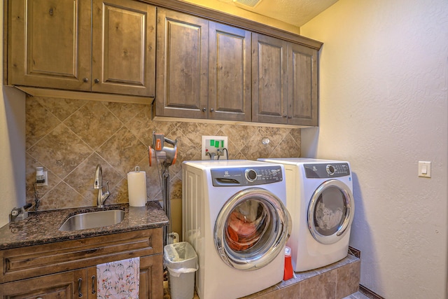 laundry room featuring washer and clothes dryer, cabinet space, a textured wall, a sink, and wet bar