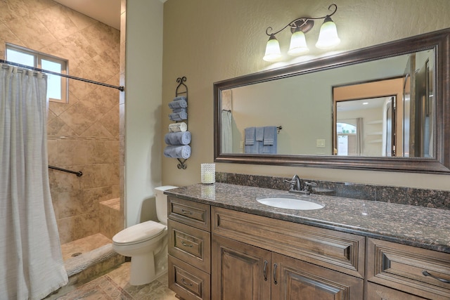 bathroom with a tile shower, vanity, and toilet