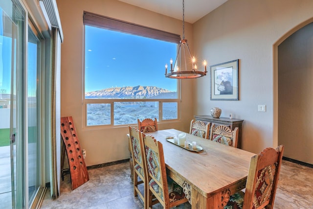 dining space featuring arched walkways, baseboards, and an inviting chandelier