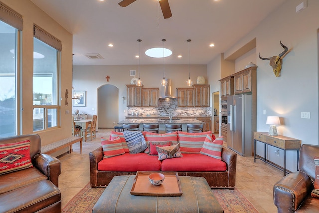 living area featuring a ceiling fan, arched walkways, visible vents, and recessed lighting