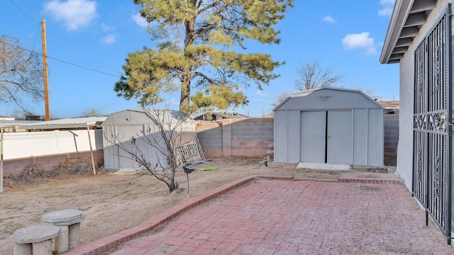 view of yard with an outdoor structure, a storage shed, a fenced backyard, and a patio area