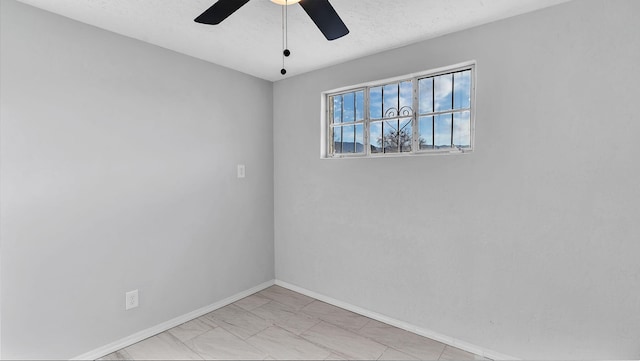 spare room featuring baseboards, a textured ceiling, and ceiling fan