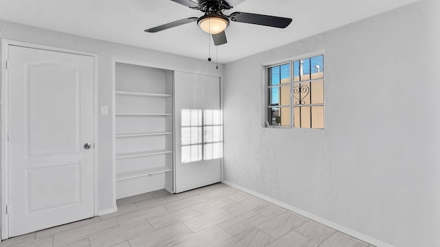 interior space with a closet, baseboards, a ceiling fan, and a textured wall