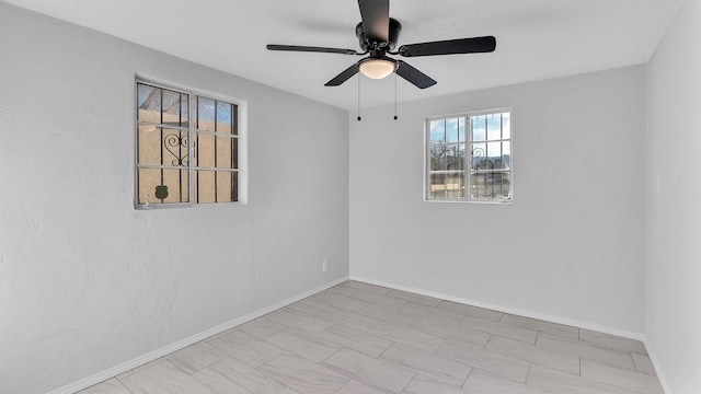 empty room with a ceiling fan and baseboards