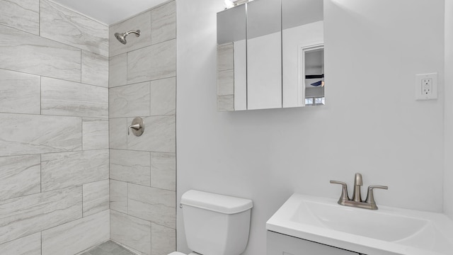 bathroom with vanity, toilet, and tiled shower