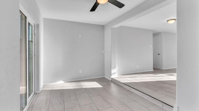 unfurnished room with baseboards, ceiling fan, and wood tiled floor