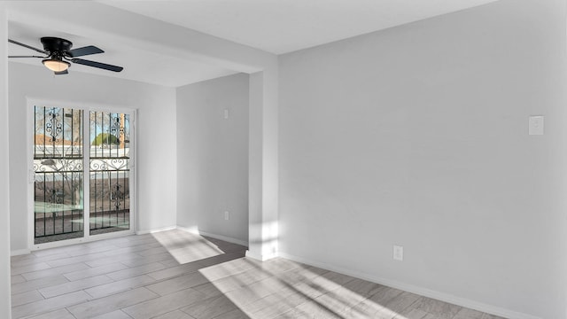 spare room featuring wood finish floors, baseboards, and ceiling fan