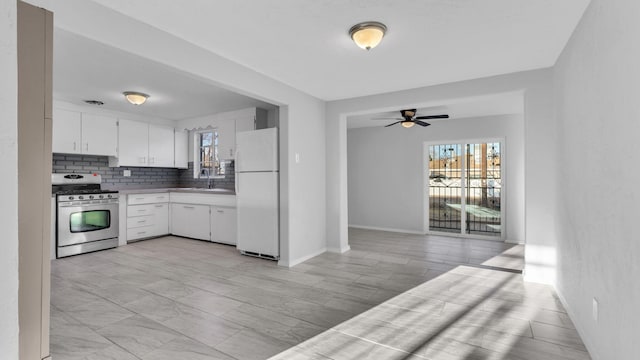 kitchen featuring tasteful backsplash, gas range, freestanding refrigerator, white cabinets, and a ceiling fan