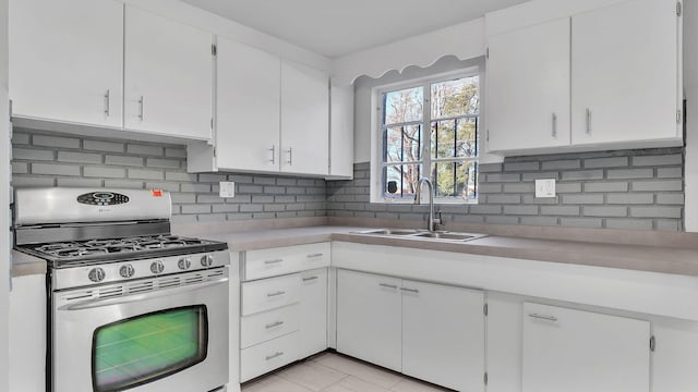 kitchen with a sink, white cabinets, light countertops, decorative backsplash, and stainless steel gas range