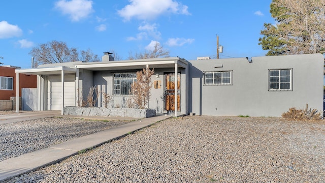 ranch-style home with a garage, concrete driveway, a chimney, and stucco siding