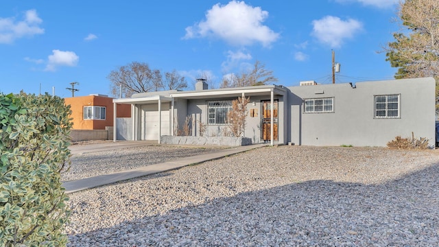 view of front of house featuring an attached garage, a chimney, and stucco siding