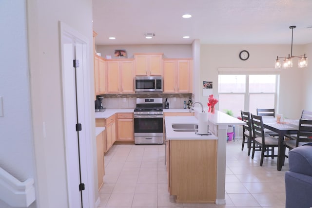 kitchen with light brown cabinetry, light countertops, decorative backsplash, stainless steel appliances, and a sink