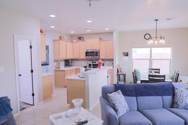 kitchen featuring light brown cabinets, open floor plan, and appliances with stainless steel finishes