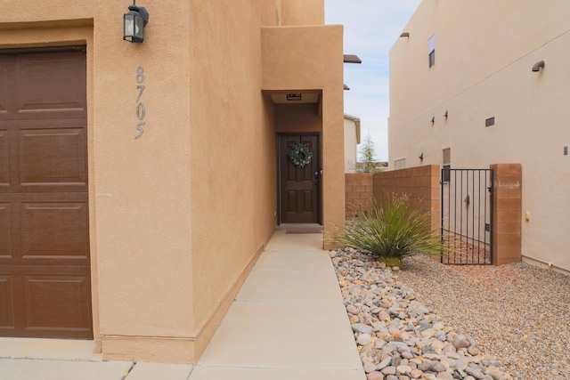 property entrance featuring stucco siding, fence, and a gate