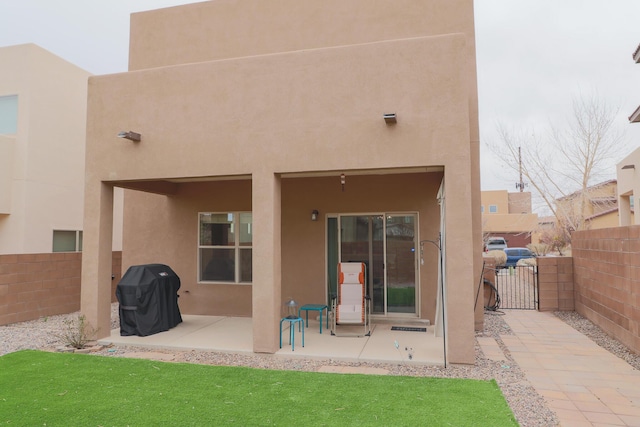 back of property with a patio area, stucco siding, a gate, and fence