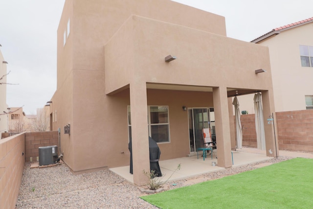 rear view of house featuring a patio area, stucco siding, cooling unit, and a fenced backyard