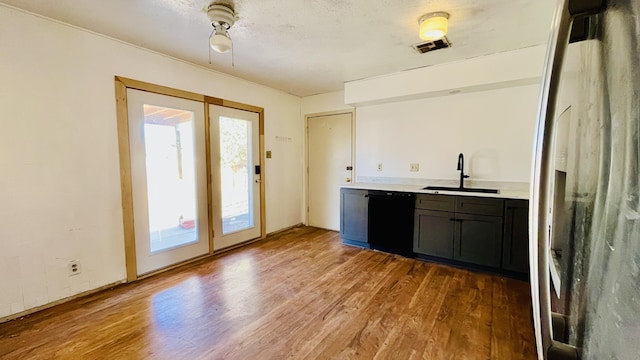 bar featuring light wood finished floors, visible vents, dishwasher, stainless steel fridge with ice dispenser, and a sink