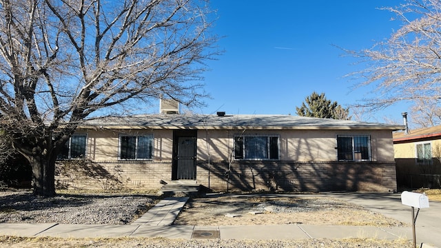 ranch-style house with brick siding, a chimney, and stucco siding