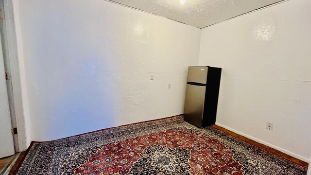 empty room featuring baseboards, a textured ceiling, and a textured wall