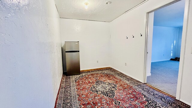 unfurnished room featuring carpet, baseboards, and a textured ceiling