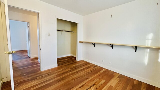 unfurnished bedroom with a closet, baseboards, and wood finished floors