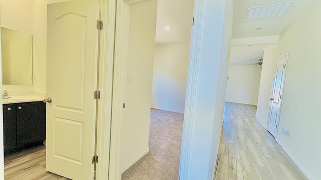 corridor featuring visible vents, light wood-style flooring, and baseboards