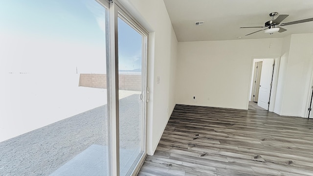 empty room with wood finished floors, visible vents, and a ceiling fan