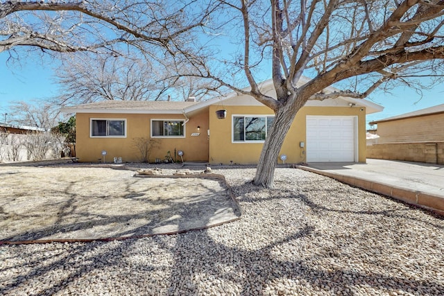 ranch-style home featuring driveway, an attached garage, and stucco siding