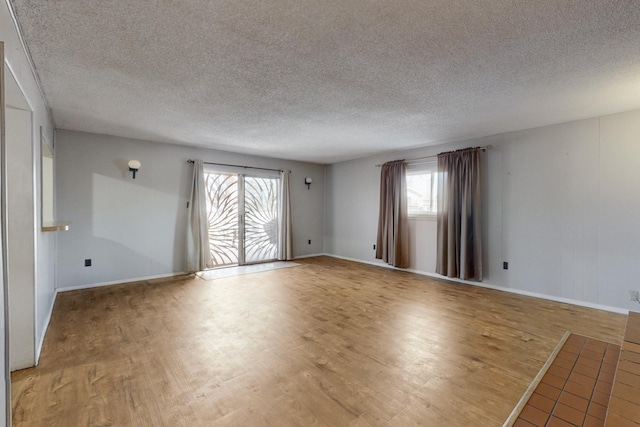 unfurnished room with light wood-type flooring, baseboards, and a textured ceiling