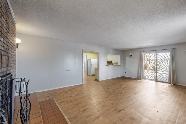 unfurnished living room with light wood-style floors, a fireplace, baseboards, and a textured ceiling