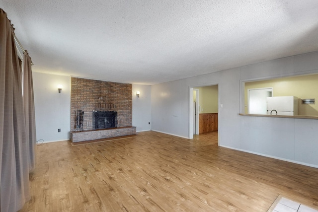 unfurnished living room featuring a fireplace, a textured ceiling, and wood finished floors