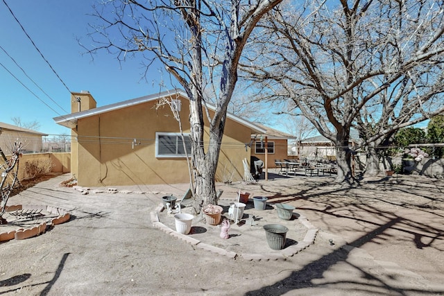 rear view of house with a patio area, fence, and stucco siding