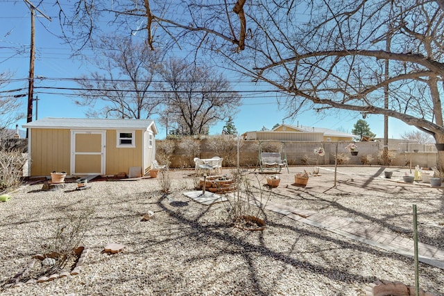 view of yard with a storage shed, a fenced backyard, a patio area, and an outbuilding