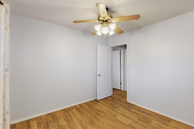 empty room featuring baseboards, a ceiling fan, and light wood-style floors