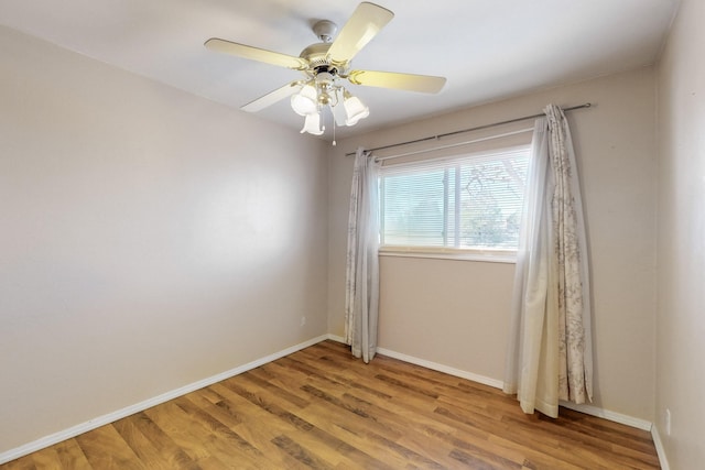 empty room with ceiling fan, baseboards, and wood finished floors